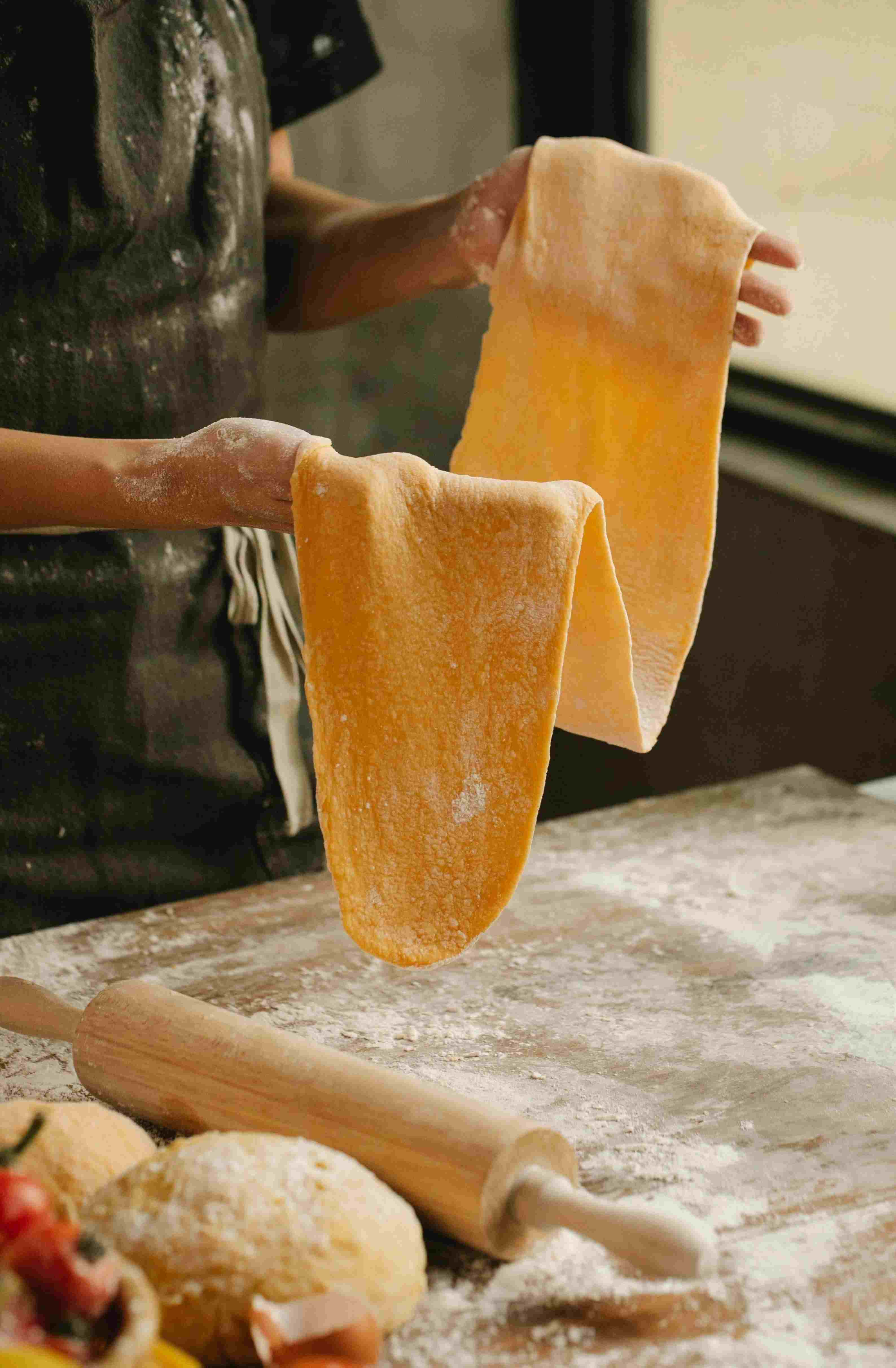A baker shaping dough on a floured wooden counter